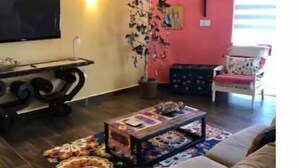 Een woonkamer met een bank, een bijzettafeltje, een televisie en een decoratieve plant.