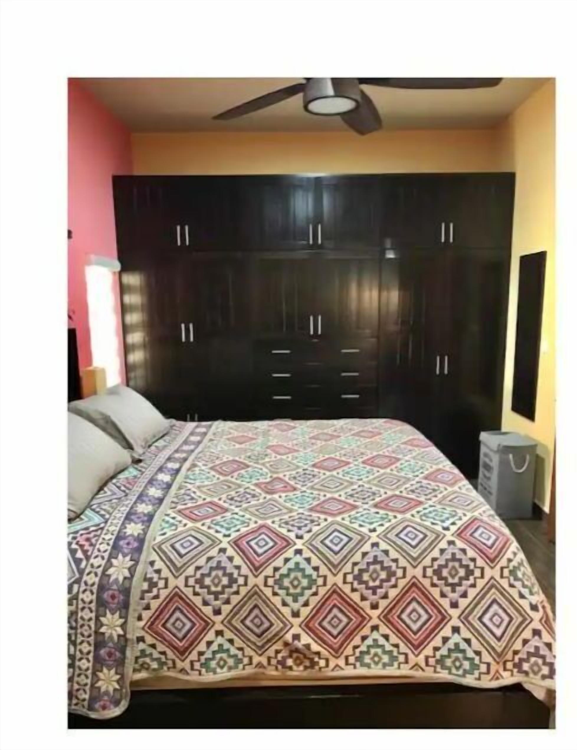 A bedroom with a bed, a ceiling fan, and a wardrobe.