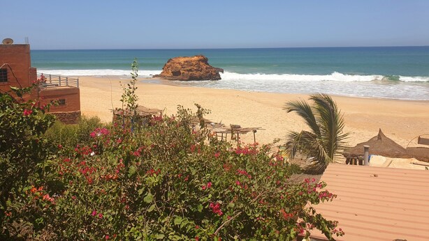 A beach with a rocky outcrop, a sandy shore, and a clear blue sky. - Pieds Dans L'eau : Grand Studio Avec 2 Lits Double et Terrasse Devant L'océan (toubab dialaw)