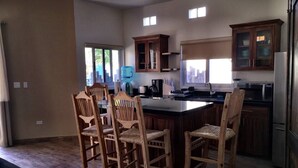 A modern kitchen with wooden cabinets, a central island, and a dining area with four chairs. - 8AP Beautiful 1st Floor Condo, Pool Side, Cerritos
 (El Pescadero)