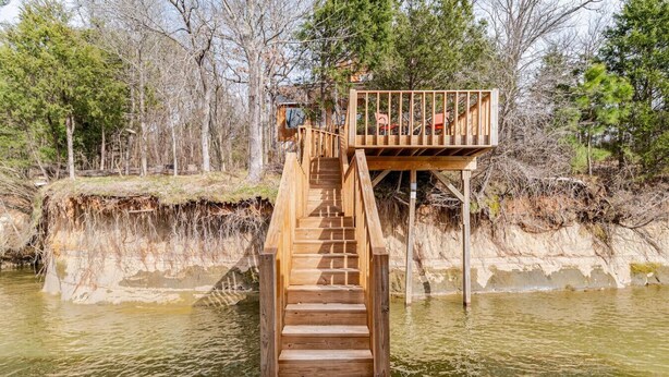 Een houten terras dat over het water uitloopt, met een platform en een hekwerk.