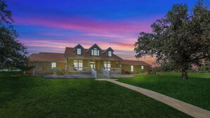 A large house with a well-maintained lawn and a pathway leading to the entrance.