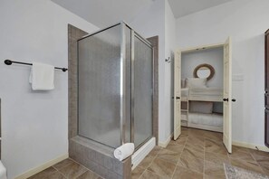 A bathroom with a glass-enclosed shower, a white sink with a mirror, and a built-in bench.
