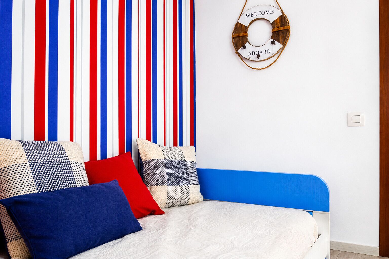 Ein Zimmer mit einem Bett, einer gestreiften Wand und einem Willkommensschild.