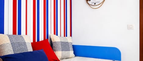Ein Zimmer mit einem Bett, einer gestreiften Wand und einem Willkommensschild.
