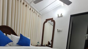 A neatly made bed with blue and white bedding, a ceiling fan, a mirror, and a door in a hotel room. - 20 min walk to Kandy city from this breezy, quite property with a parking. (Kandy)