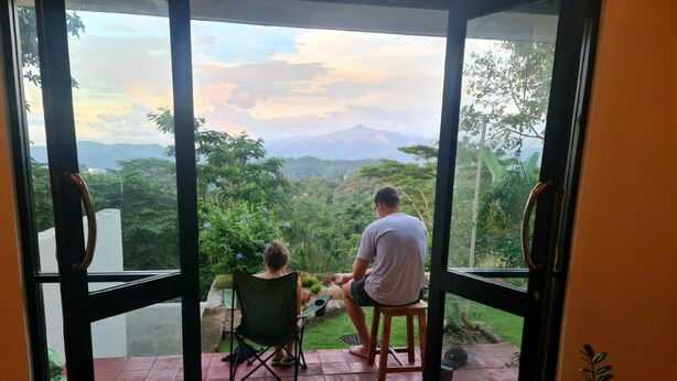 A room with a glass door leading to a balcony with a view of a mountain and greenery. - 20 min walk to Kandy city from this breezy, quite property with a parking. (Kandy)
