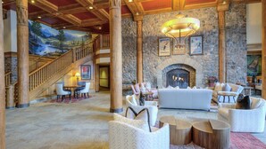 A spacious lobby with a stone fireplace, comfortable seating, and a staircase leading to upper floors. - Mccoy Peak Lodge #107 1 Bedroom Condo by RedAwning (Avon)