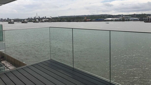 Blick vom Balkon auf einen Fluss mit Booten, eine Stadtansicht und einen bewölkten Himmel.