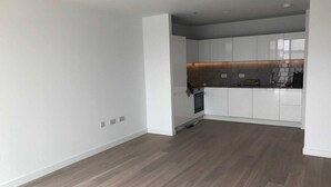 Eine moderne Küche mit weißen Schränken, einer dunklen Spritzschutzwand und Holzdielen.