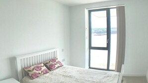 Ein Schlafzimmer mit Bett, Nachttisch und einem Fenster mit Vorhängen.