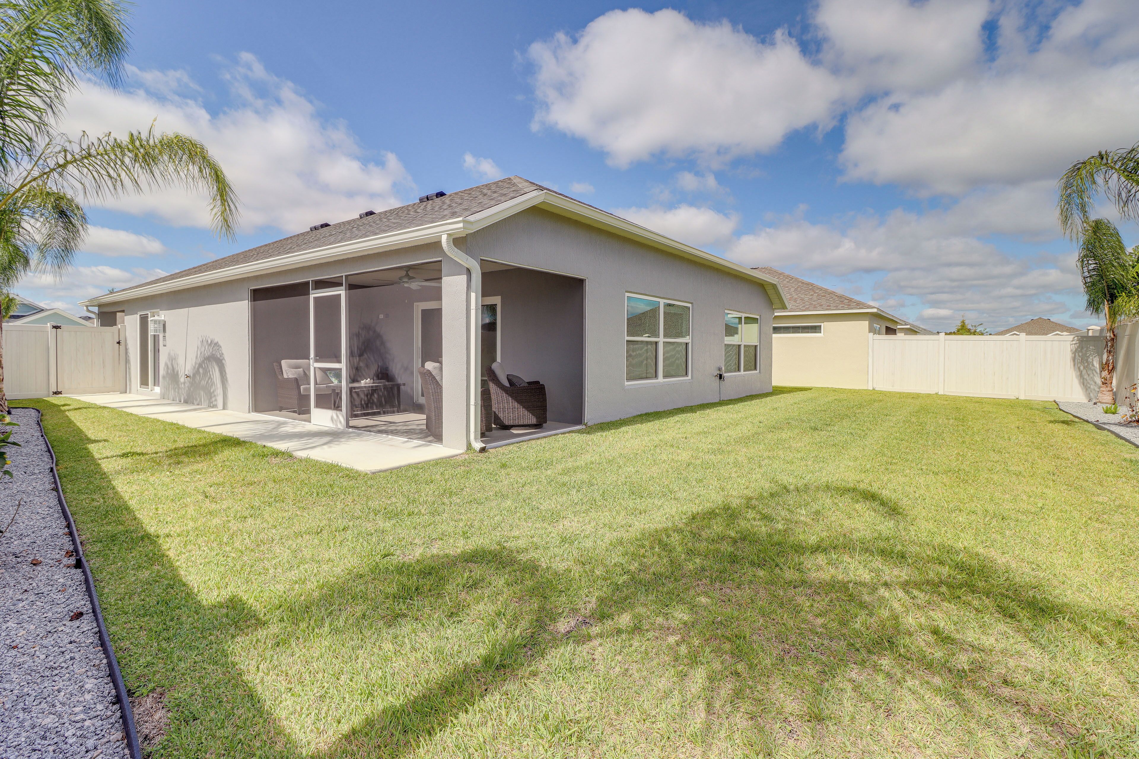 A single-story house with a covered patio, a fenced backyard, and a well-maintained lawn.