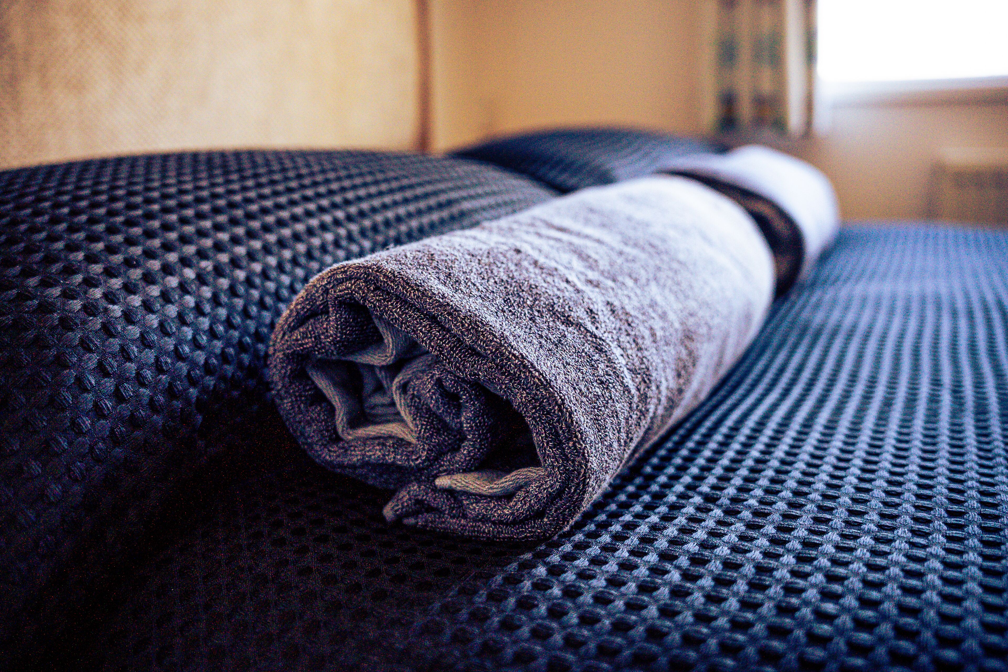 Un objeto enrollado sobre una superficie texturizada, posiblemente una toalla o manta, con un diseño de puntos pequeños en relieve.