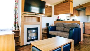A compact living space with a flat-screen TV mounted above a fireplace, a sofa, and a dining table.