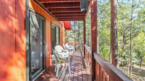 A wooden deck with outdoor seating and a view of the forest.