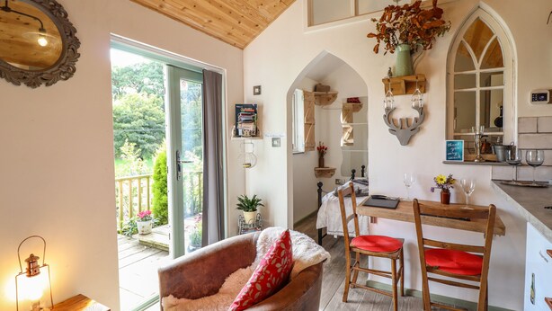 Una camera accogliente con soffitto in legno, un'area pranzo con tavolo e sedie, un camino e vista sull'esterno.