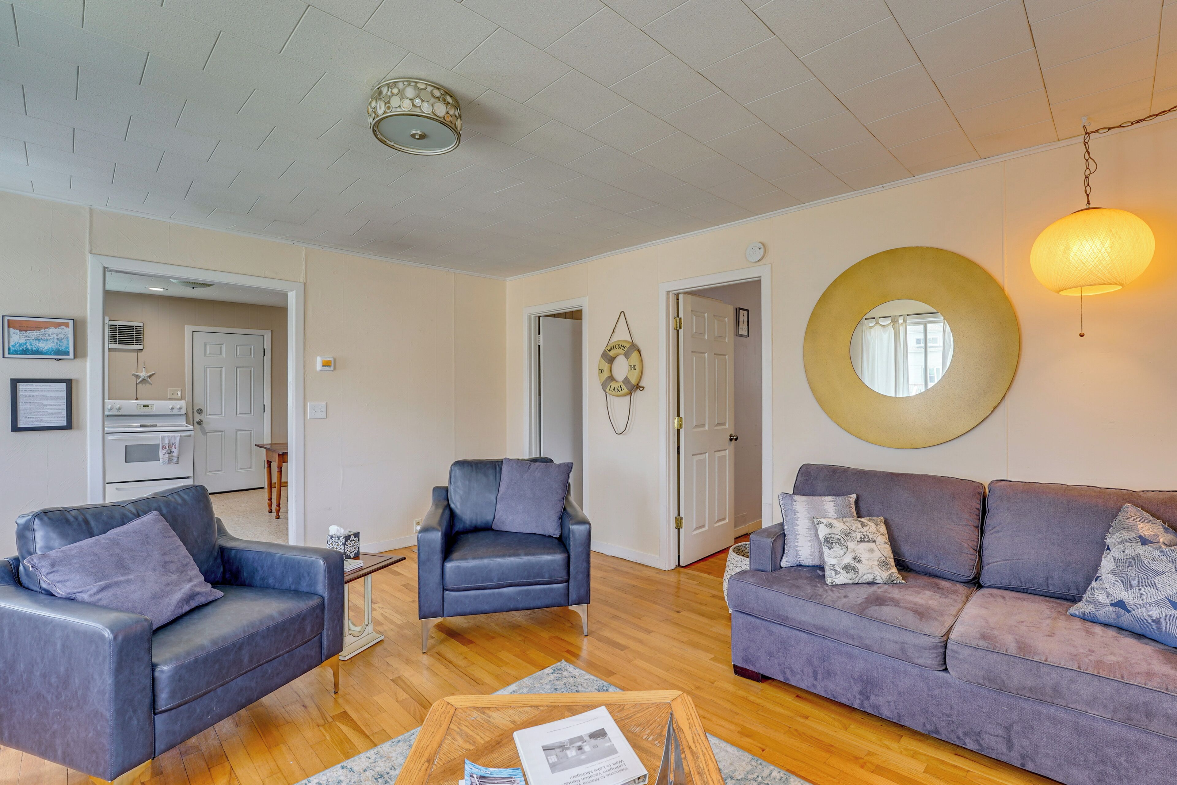 A living room with two sofas, a coffee table, and a fireplace. There is a kitchen in the background.