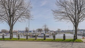 A waterfront view with a marina, boats, and trees along the shore. - Ludington Vacation Rental - Walk to Lake Michigan! (Ludington)