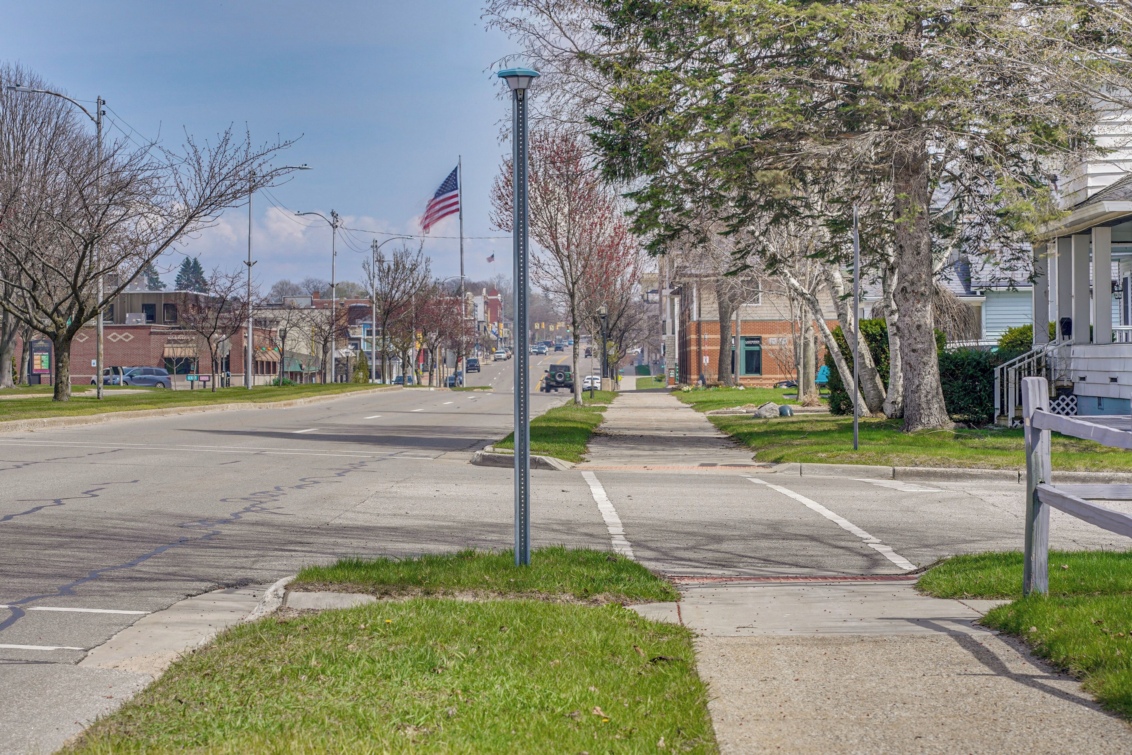 Une rue paisible dans un quartier résidentiel, avec un trottoir, des lampadaires et une rangée de maisons.