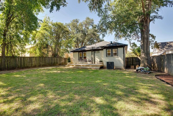 A residential backyard with a house, a wooden fence, and a large tree. - Walk to Dtwn: 'tyler Tudor' w/ Backyard (Tyler)