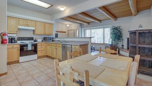 Una cocina amplia con armarios de madera, una mesa de comedor y un ventanal grande.