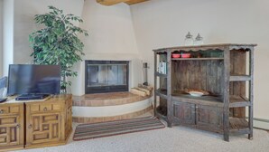 Una sala de estar con chimenea, muebles de madera y un televisor.