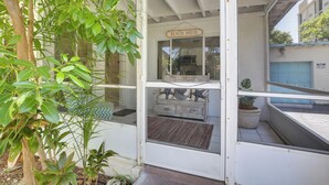 A beach house with a glass door, a sign above the door, and a small balcony with a potted plant. - Walk to Ocean: Chic Deerfield Beach Cottage! (Deerfield Beach)