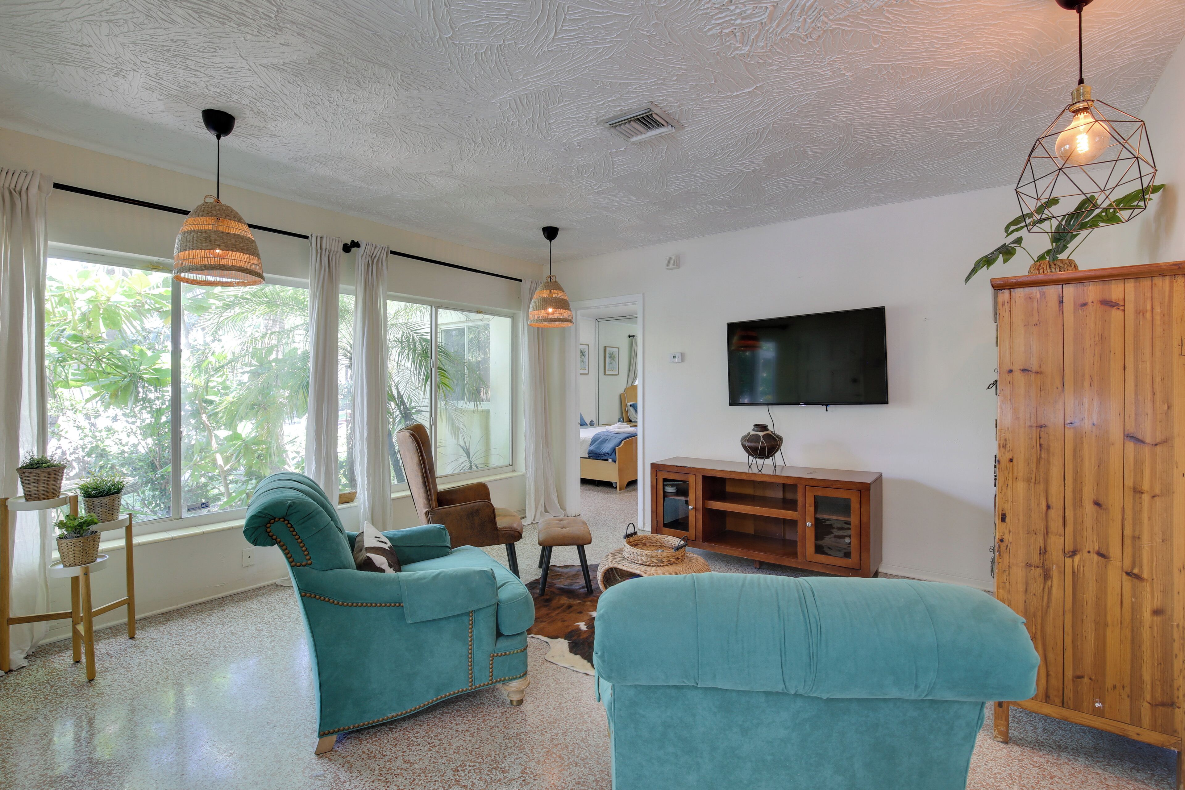 Ein Wohnzimmer mit petrolfarbenen Sofas, einem Holzkasten und einem Fernseher an der Wand.