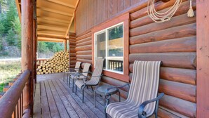 Eine Blockhütte mit einer Holzterrasse, Sitzgelegenheiten im Freien und einem Holzstapel.