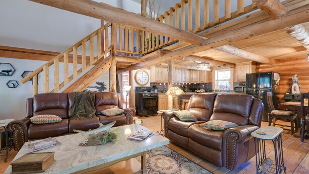 Ein geräumiges Wohnzimmer mit Ledersofas, einem Marmortisch und einer Holztreppe.