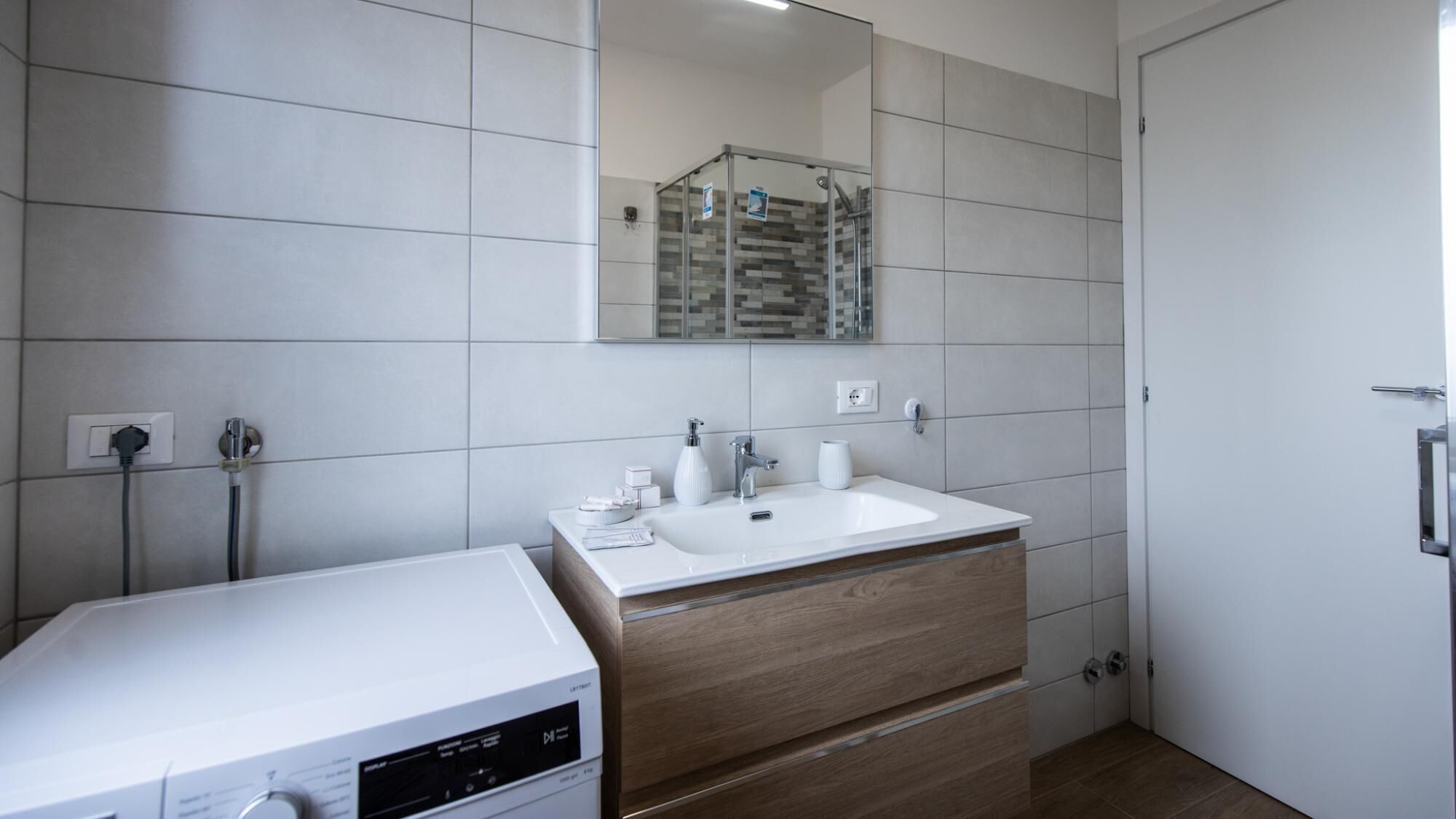 Ein modernes Badezimmer mit einem weißen Waschbecken, einem Holzschrank und einer Duschkabine.