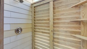 Pared exterior de madera con una puerta metálica y un ventanal.