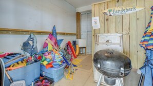 Un garaje desordenado con una parrilla para barbacoa, varias herramientas y un letrero que dice 'Landshark Margaritaville'.