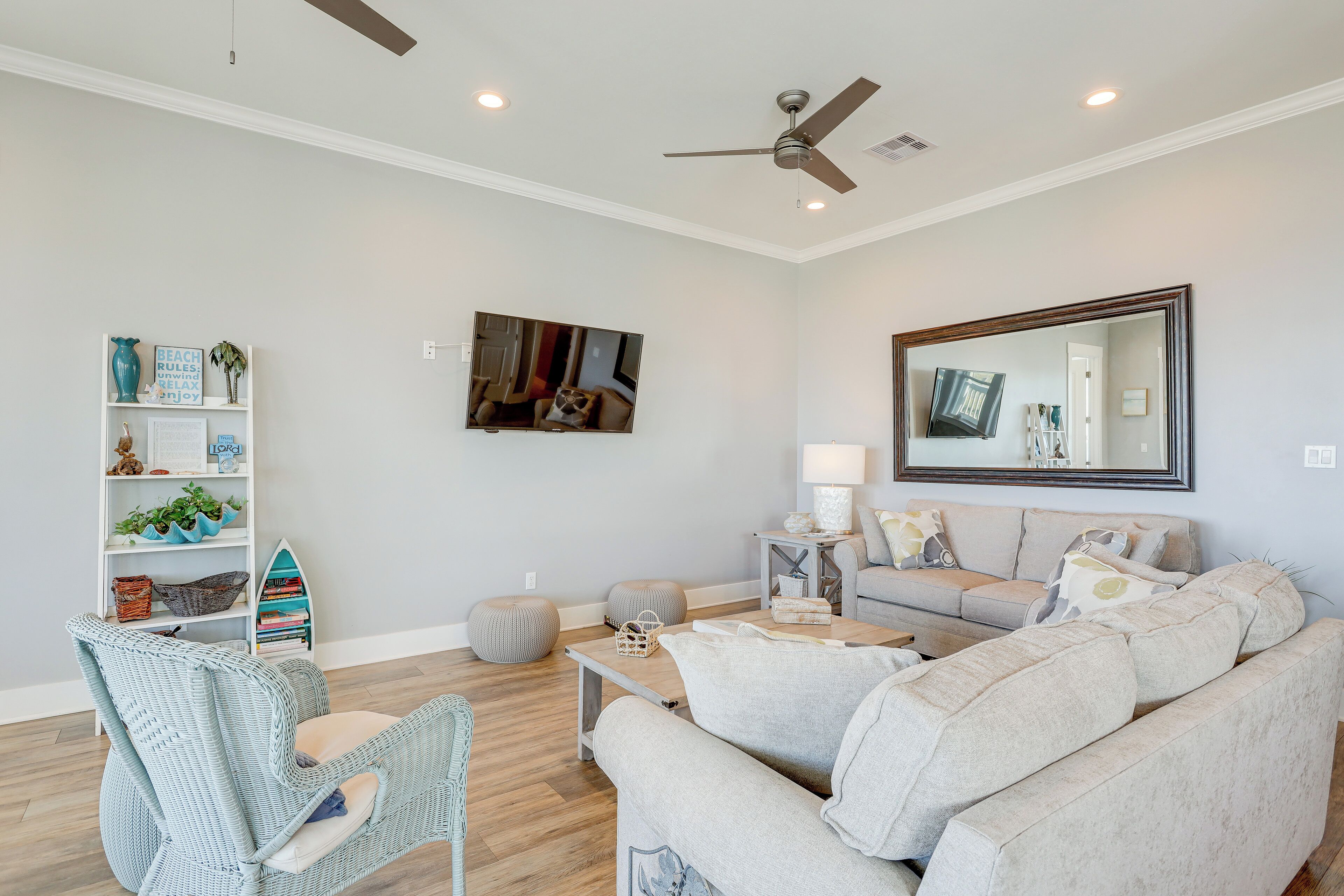 A living room with a sofa, a chair, a coffee table, a bookshelf, and a ceiling fan.