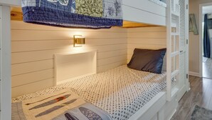 A bunk bed with a quilted headboard, a bedside lamp, and a patterned bedspread.
