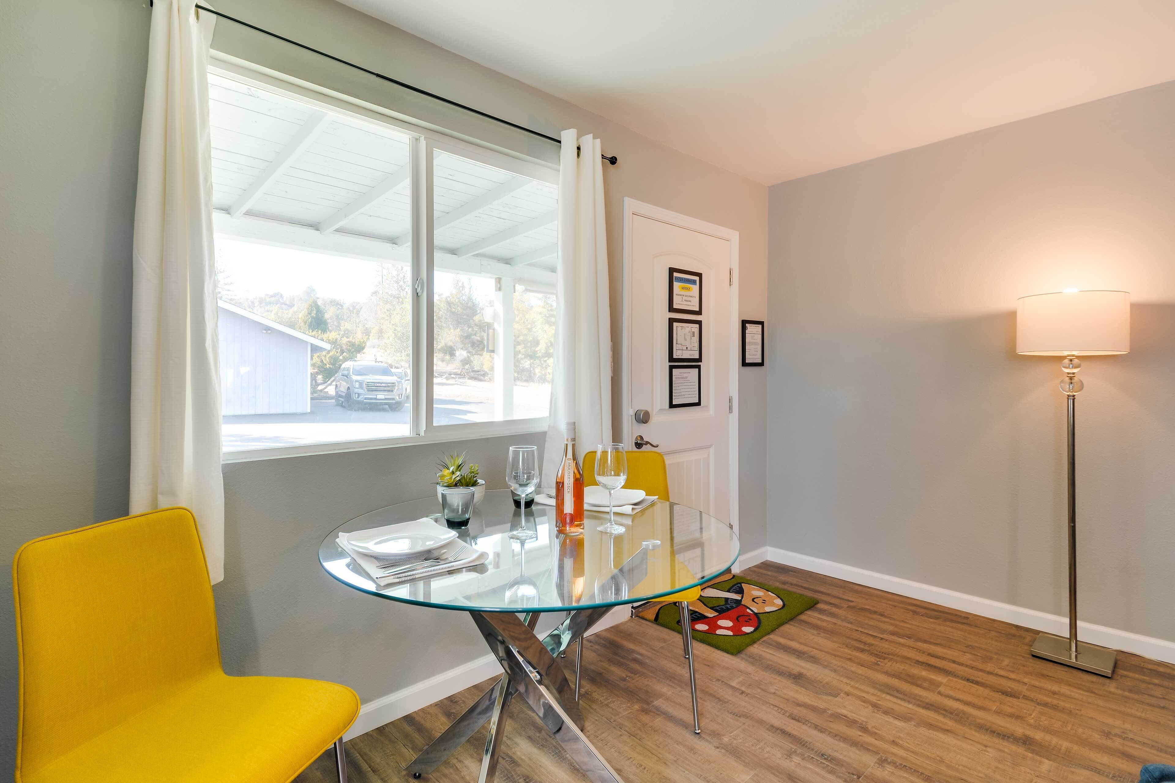 A dining area with a glass table, yellow chairs, a small potted plant, and a lamp.