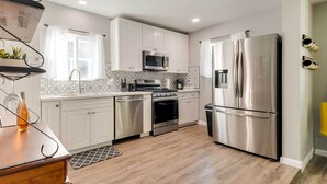 Una cocina moderna con armarios blancos, electrodomésticos de acero inoxidable y una mesa de comedor de madera.