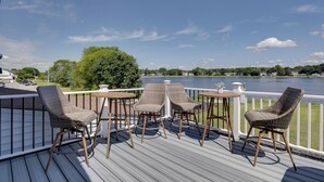 En terrasse med fletstole og et bord med udsigt over en sø.