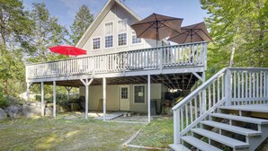 A two-story house with a balcony and a covered porch area. - Frye Island Family Cabin With Lake & Beach Access! (Raymond)
