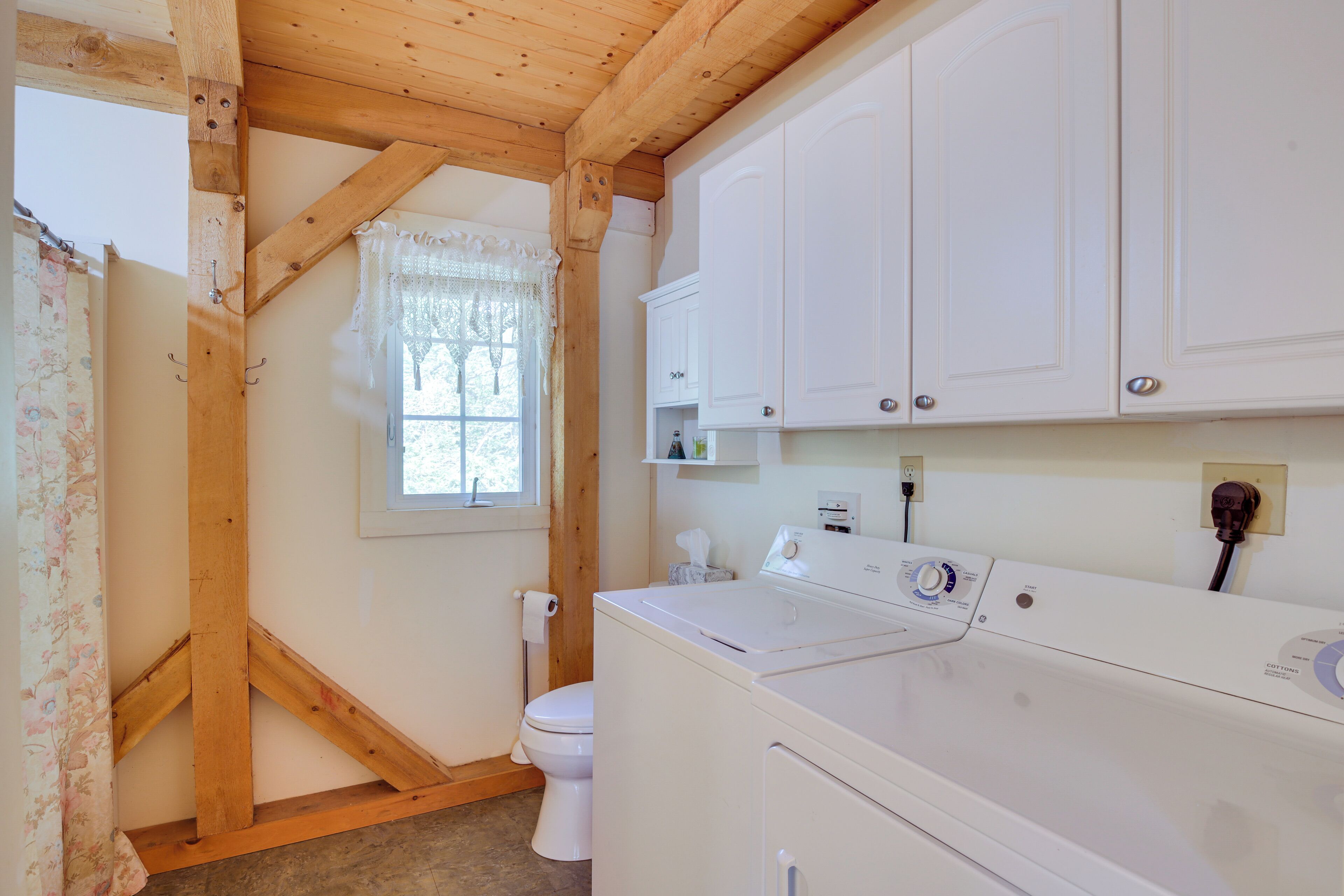 A laundry room with a washing machine, a dryer, and white cabinets.