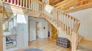 A spacious room with a wooden staircase, a white wardrobe, and a small round rug. - Frye Island Family Cabin With Lake & Beach Access! (Raymond)
