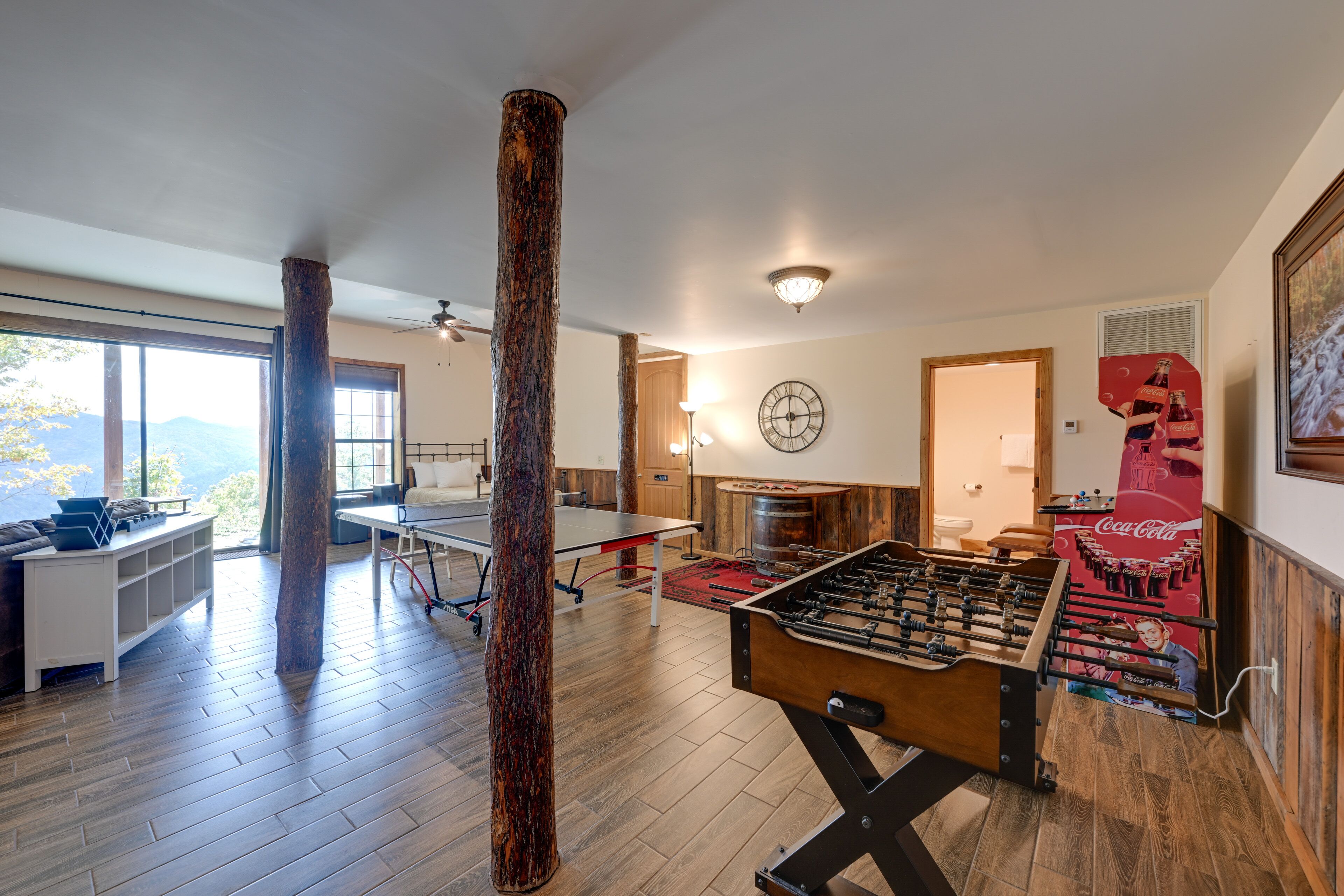 A spacious living area with a foosball table, a large wooden pillar, and a Coca-Cola mural.