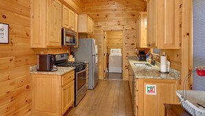 A compact kitchen with wooden cabinets, a microwave, a refrigerator, a stove, and a sink.