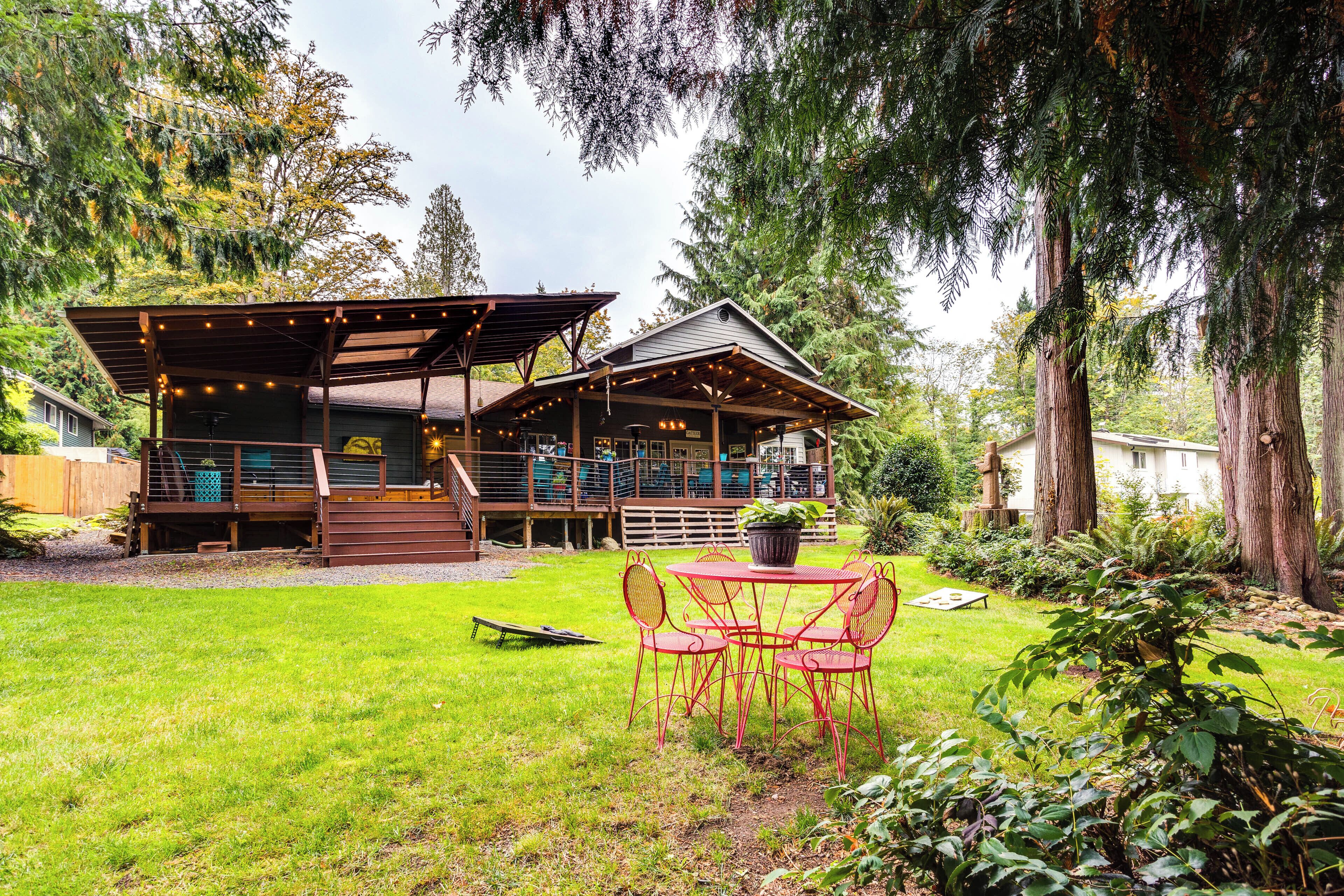 A wooden deck with string lights, a covered patio, and a dining area with red chairs.