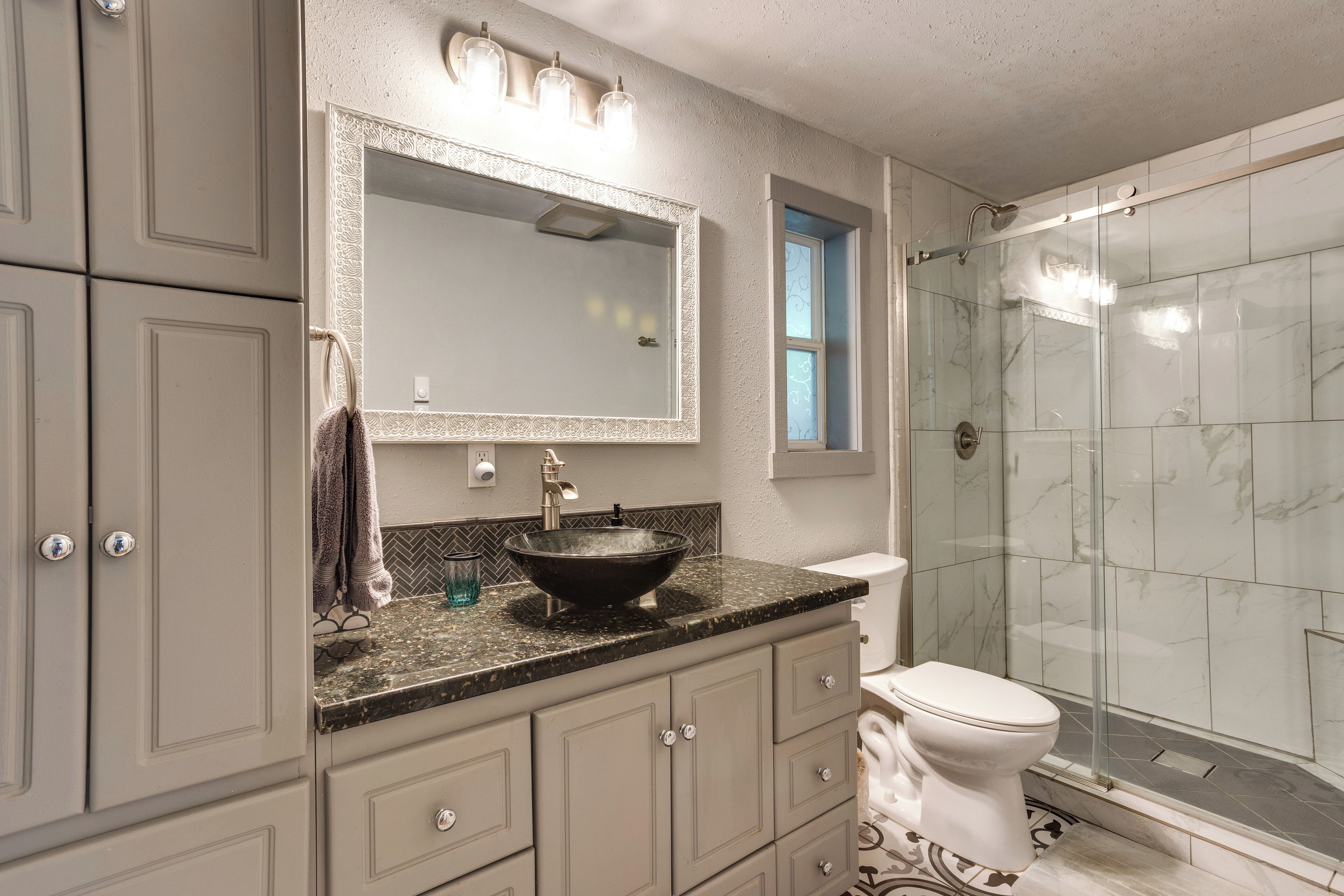 Une salle de bain dotée d’un grand miroir, d’un lavabo sur colonne, de toilettes et d’une douche à l’italienne.