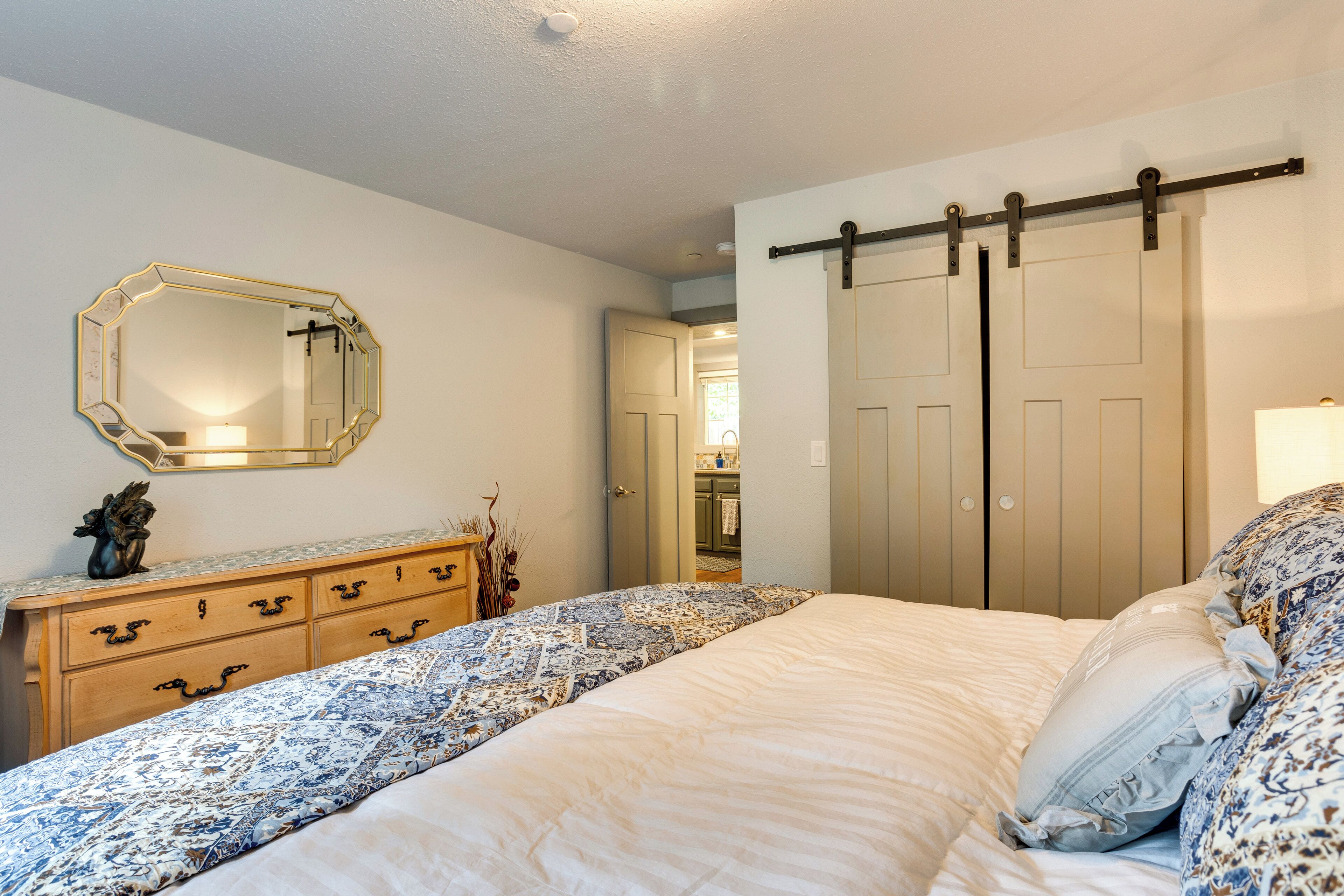 A bedroom with a bed, dresser, mirror, and sliding doors.
