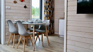 A dining area with a table set for four, surrounded by modern chairs with wooden legs. - House in Stepnica by Szczecin Lagoon (Stepnica)