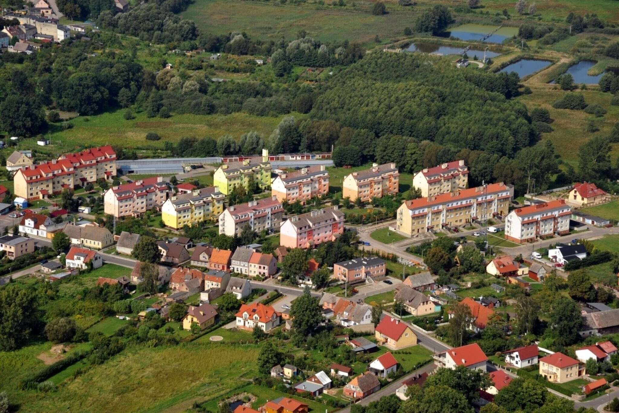 An aerial view of a residential area with multiple apartment buildings, roads, and green spaces.