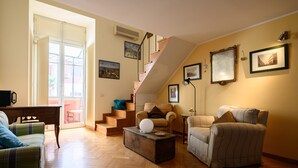 Ein Wohnzimmer mit Treppe, Sofa, Couchtisch und Sessel.