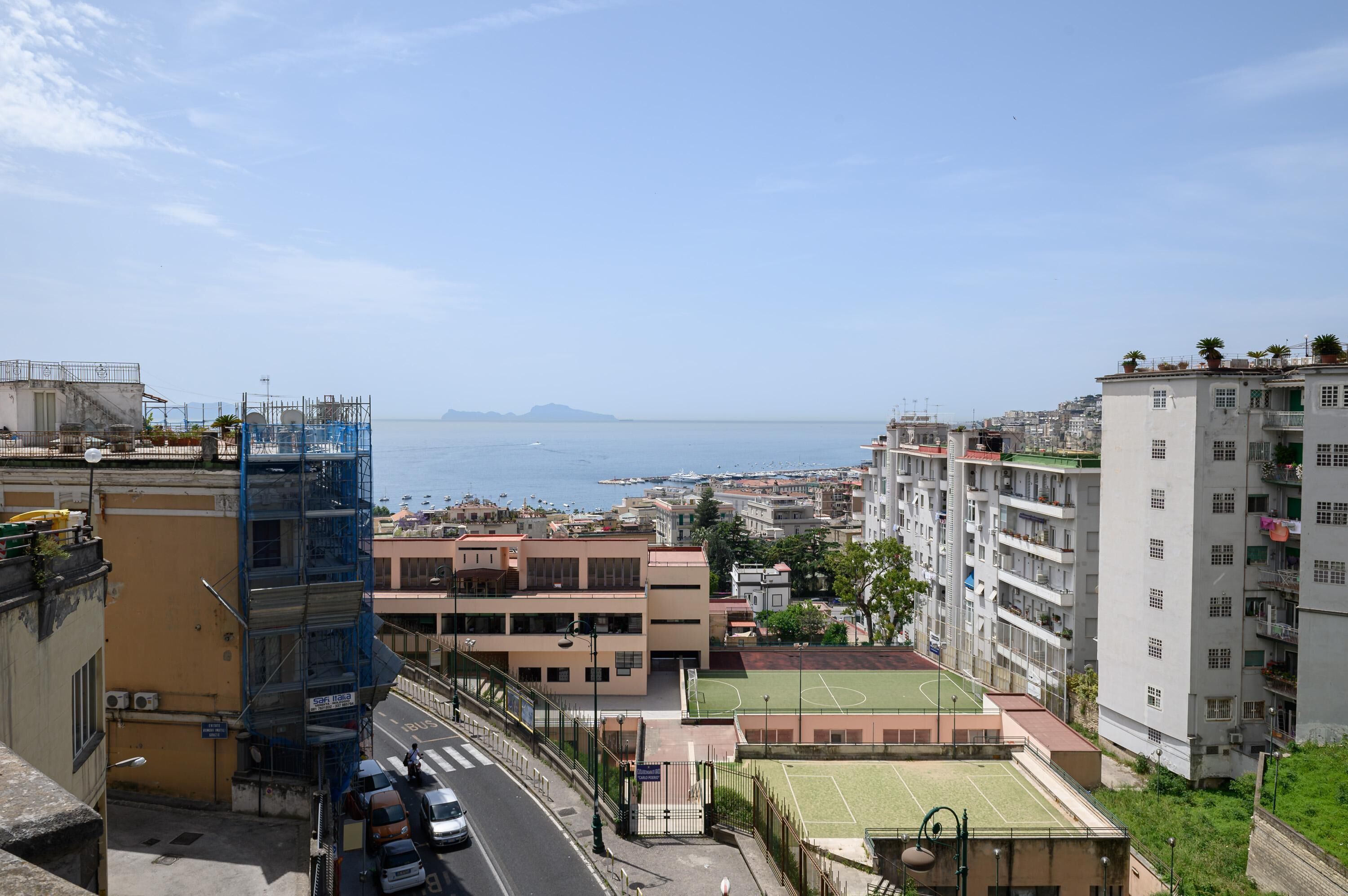A residential area with a view of the sea, buildings with balconies, and a tennis court.